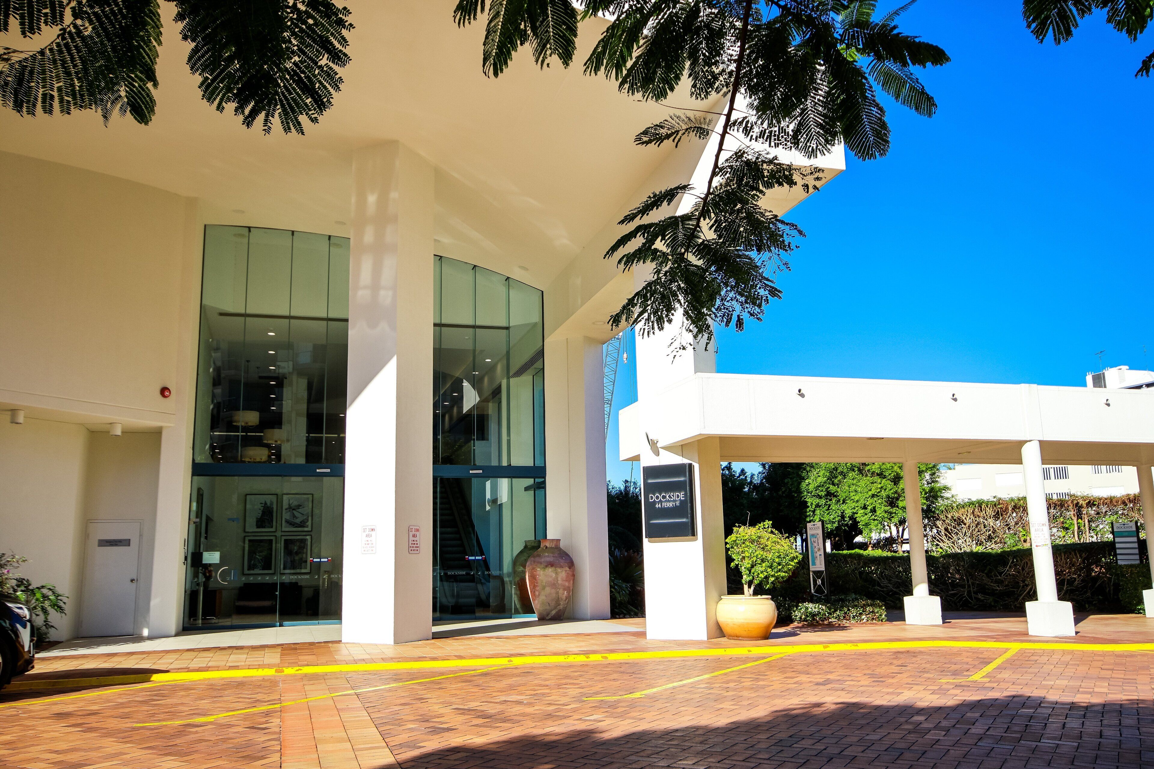 A modern building entrance with glass doors, a large planter, and a sign reading "Dockside 44".