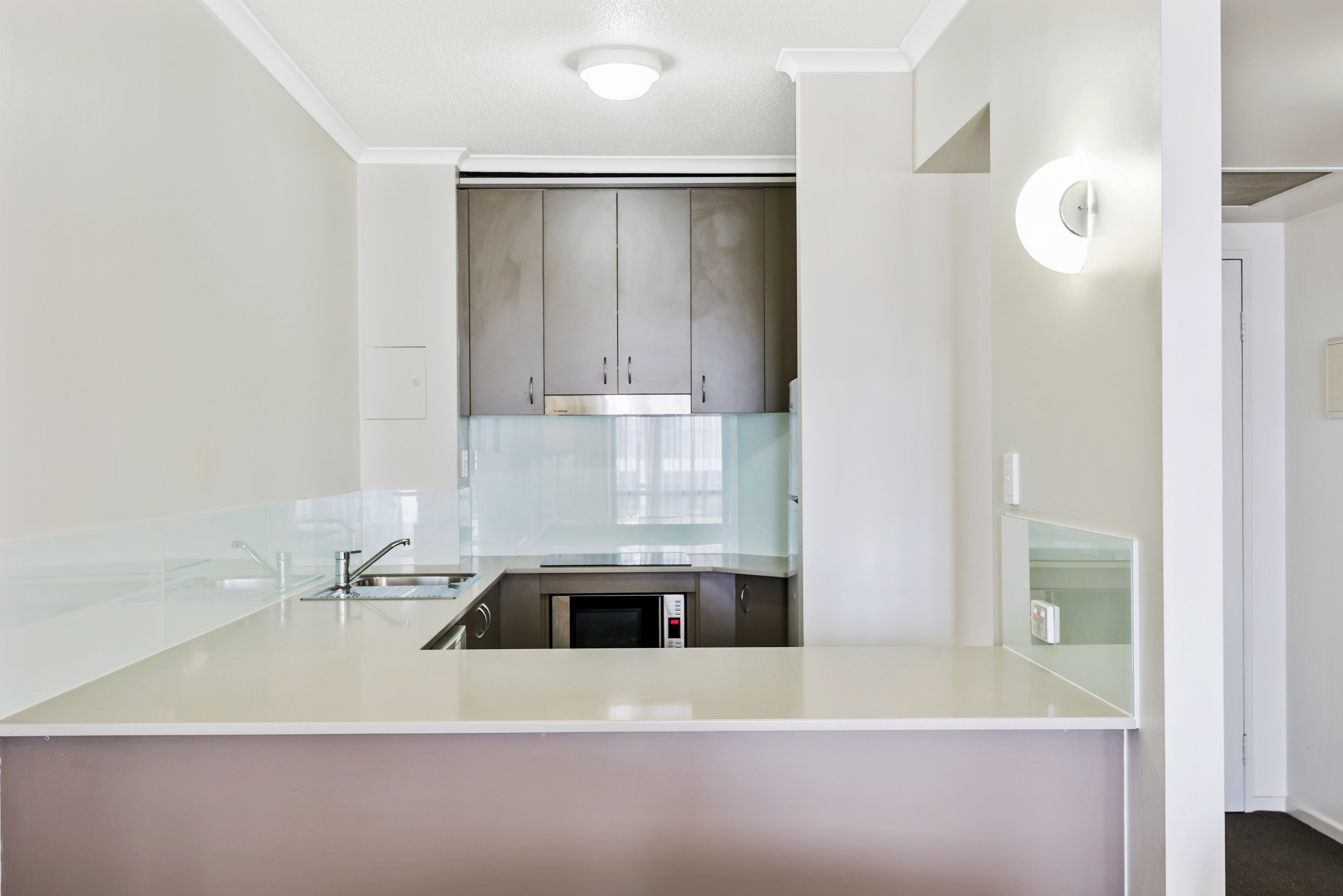 A modern kitchen with a central island, stainless steel appliances, and a glass backsplash.