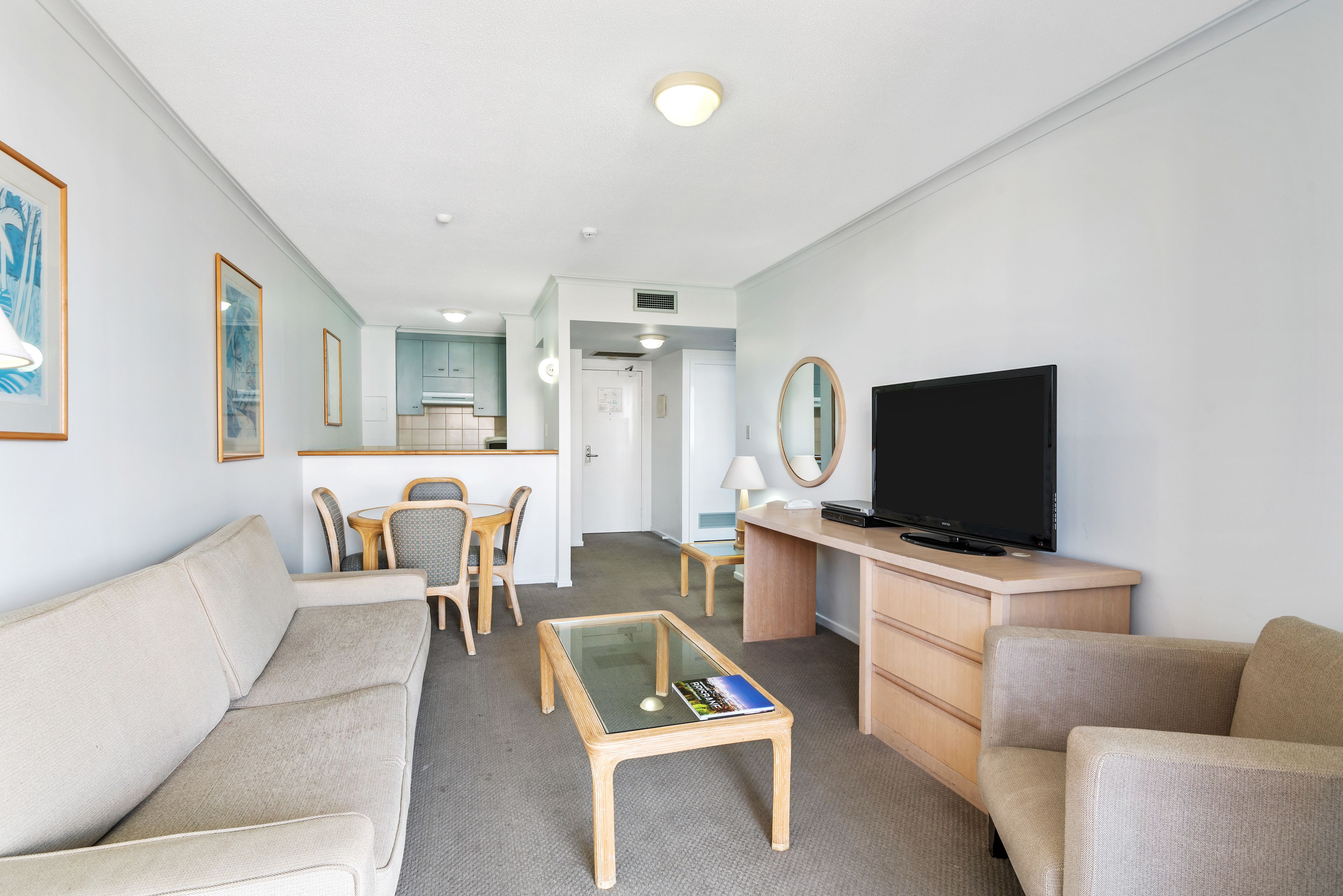 Een moderne hotelkamer met een bank, een salontafel, een televisie en een zithoek met stoelen en een tafel.