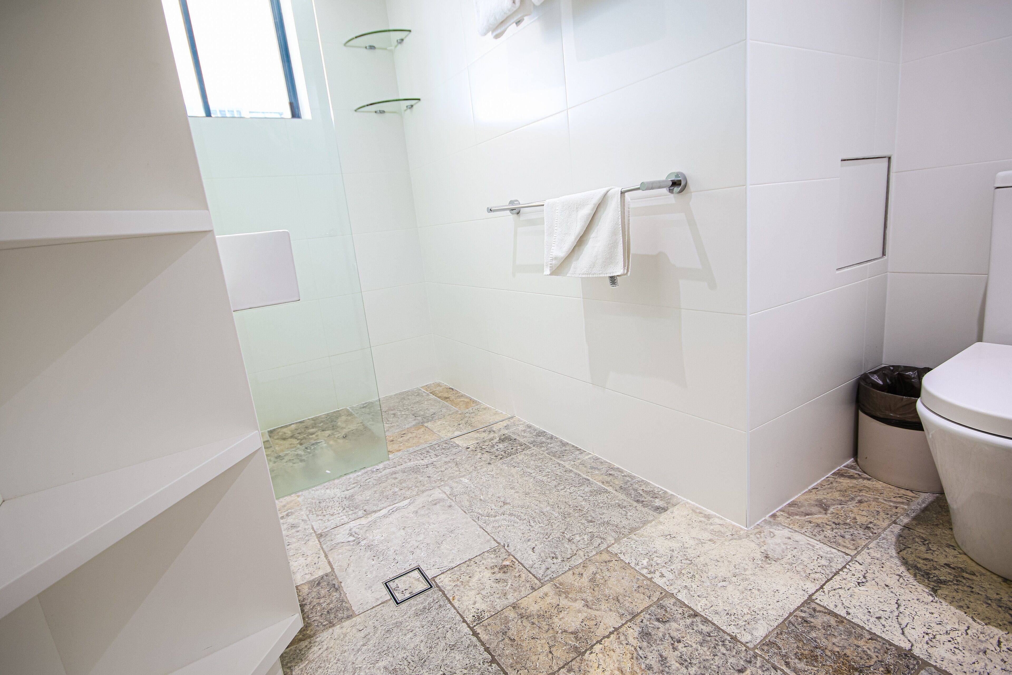 A bathroom with a shower, a toilet, and a towel rack.