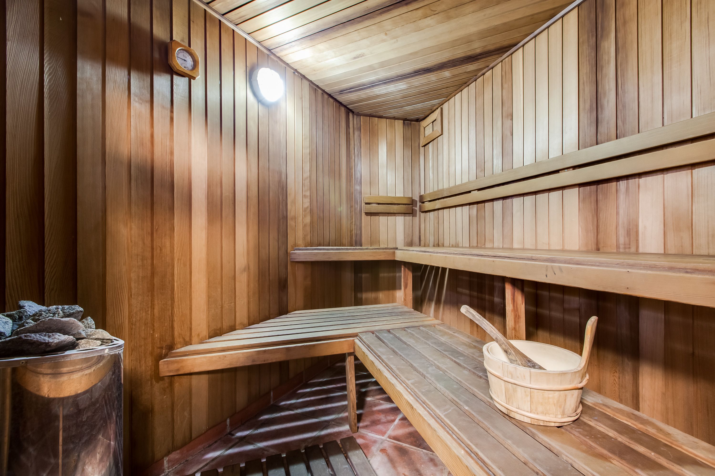 A sauna with wooden benches and a stone basin.
