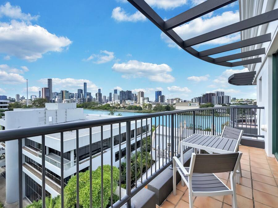 Un balcón con vista a la ciudad, una piscina y un edificio moderno al fondo.