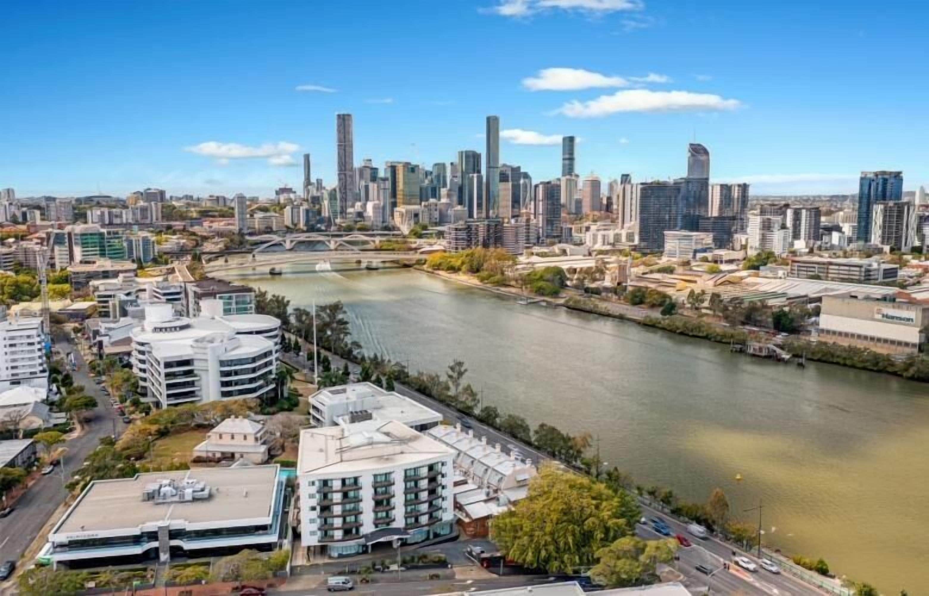 A cityscape with modern buildings, a river, and a bridge.
