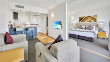 Habitación de hotel con cama, escritorio, sofá, televisor y un cuadro.