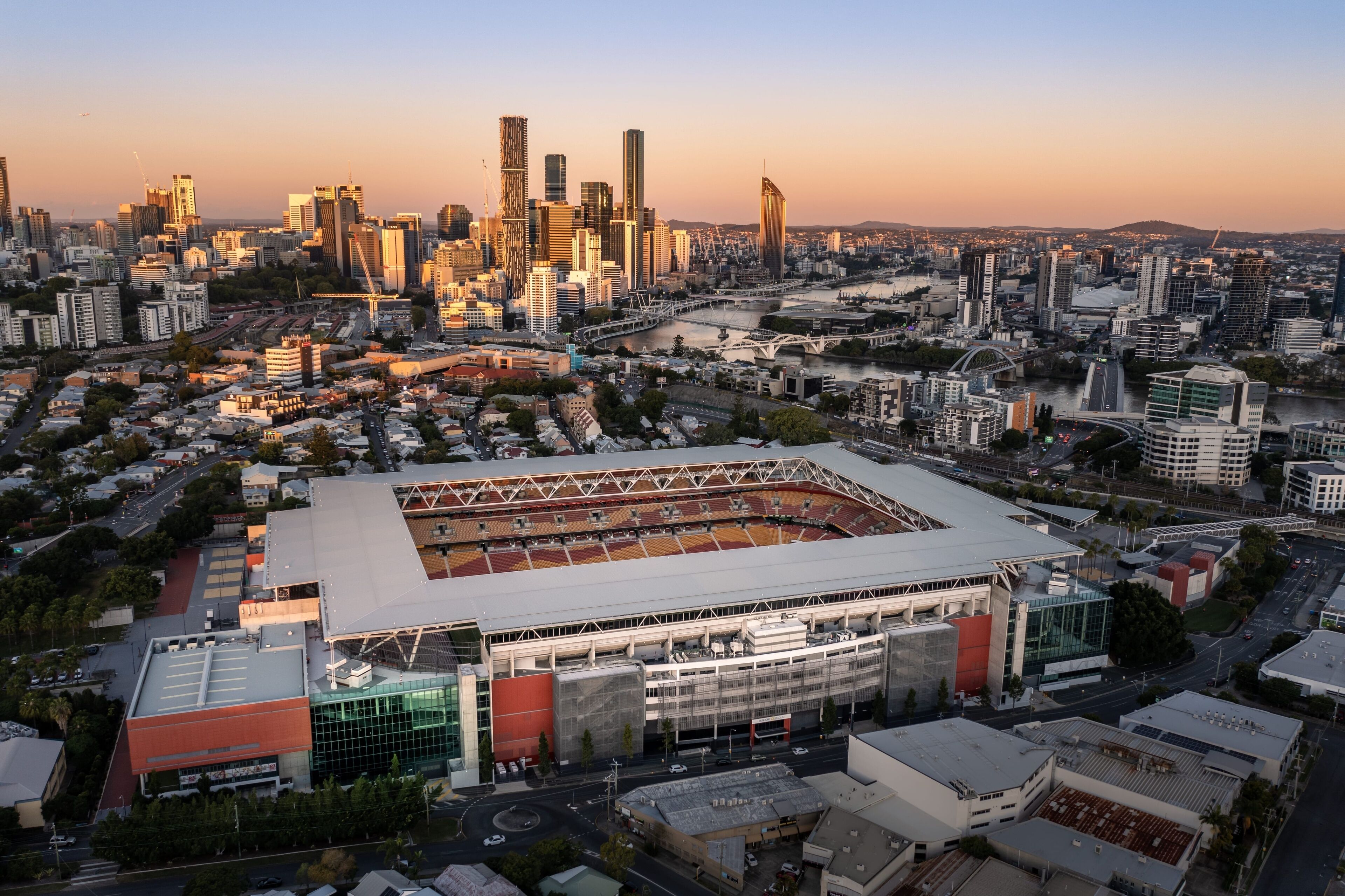 A stadium with a large central field surrounded by parking and a city skyline in the background.