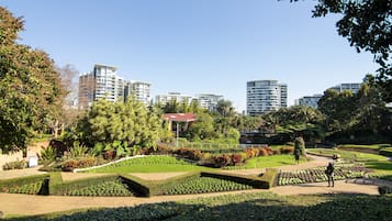 A landscaped garden with manicured lawns and pathways, surrounded by tall residential buildings.