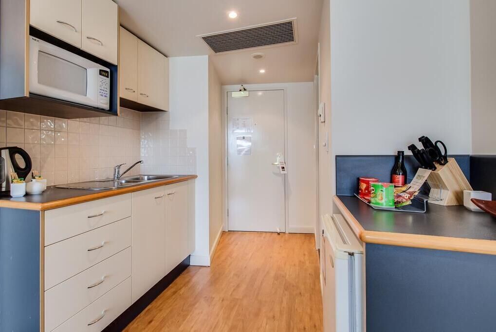 Una cocina pequeña con microondas, lavamanos y encimera de madera.