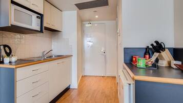 Una cocina pequeña con microondas, lavamanos y encimera de madera.