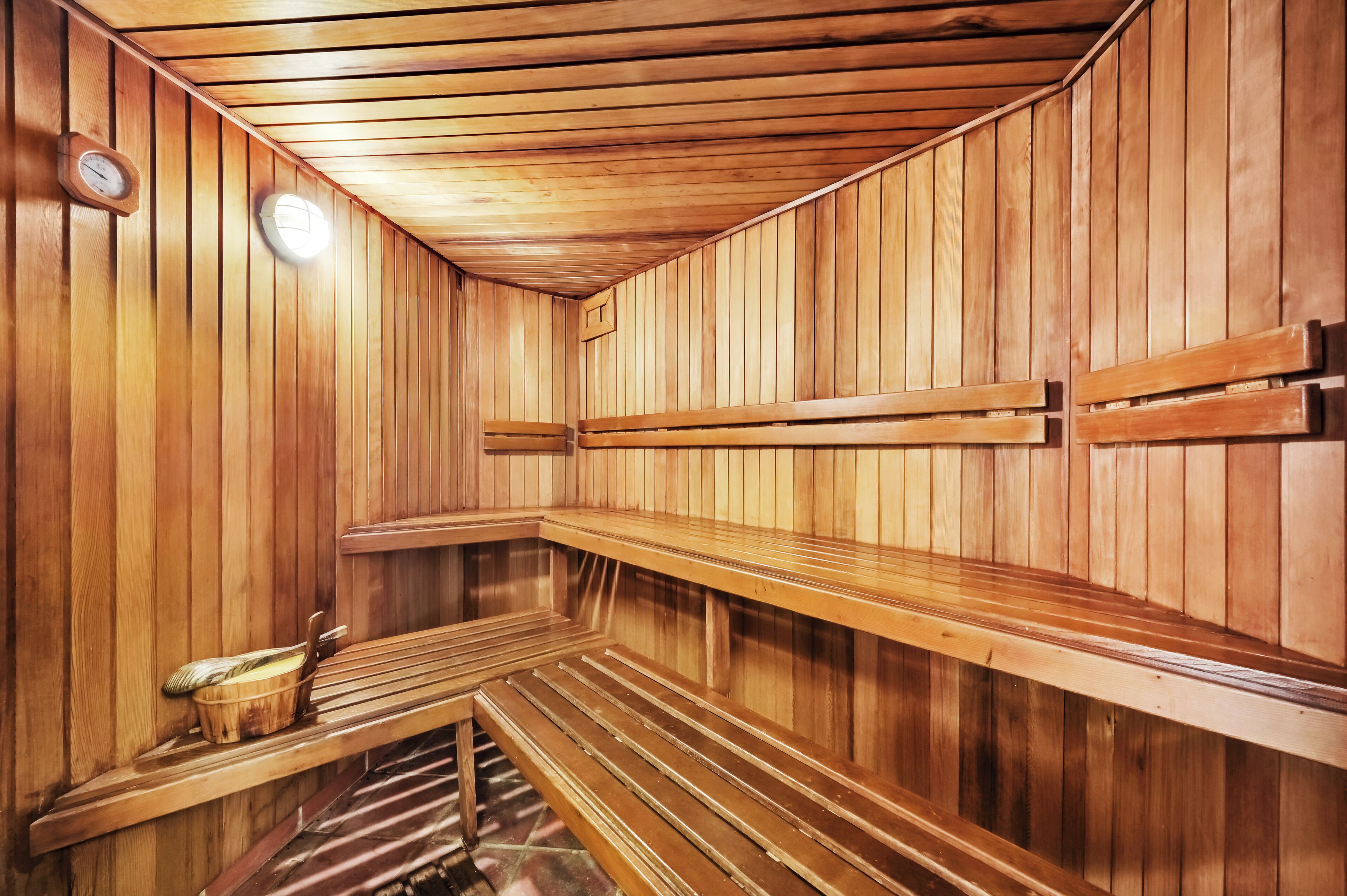 Een sauna met houten banken en een bankje met een handdoek en borstel.