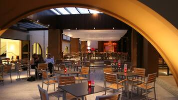 An indoor dining area with tables and chairs, a central stage, and a skylight.