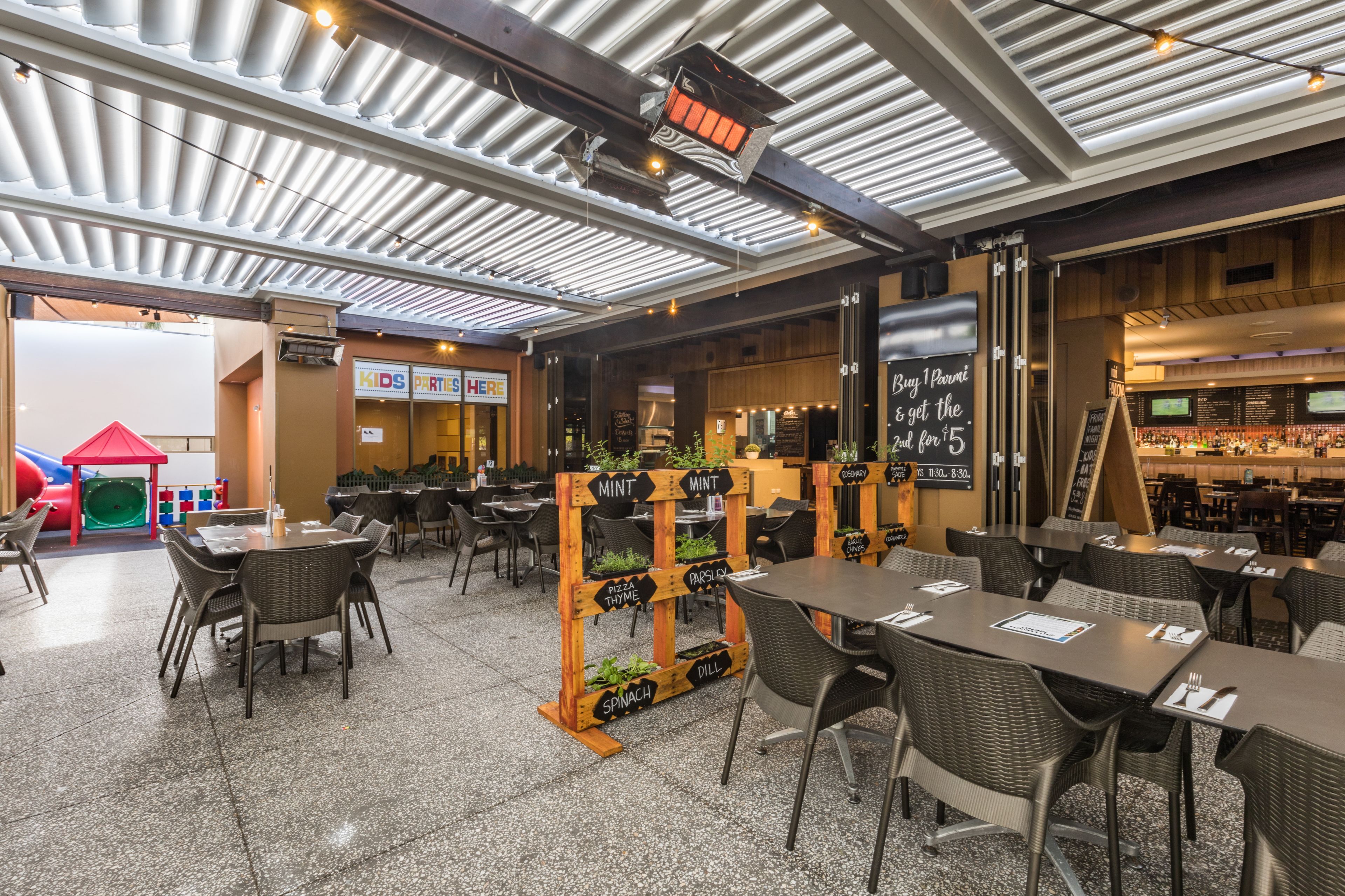 Een restaurantruimte met tafels en stoelen, een speelruimte voor kinderen en een bar.
