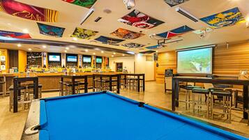 A bar area with a pool table, multiple bar counters, and a projection screen.
