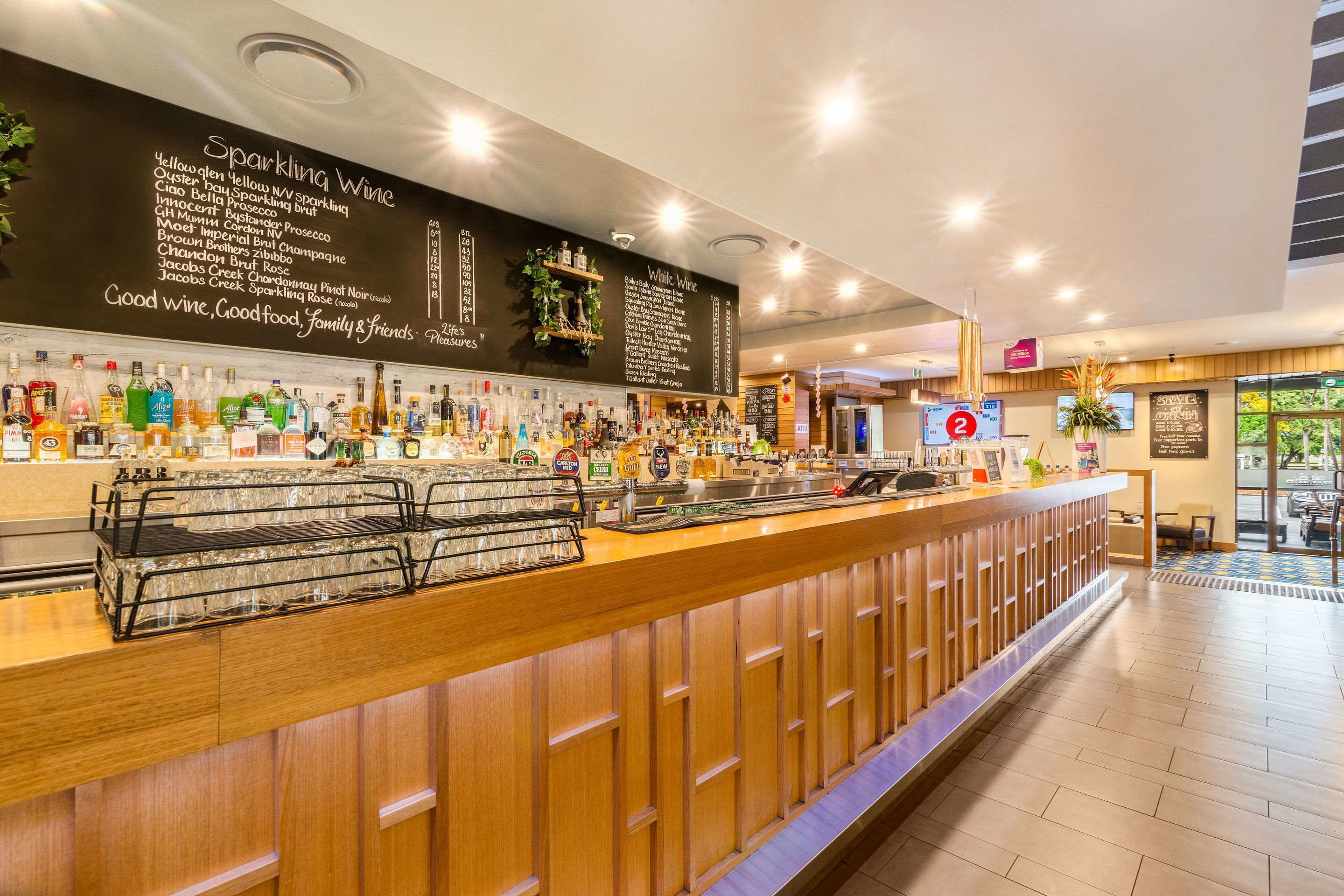 Un espace bar doté d’un tableau noir affichant la carte des vins et d’un comptoir où sont exposées différentes bouteilles.