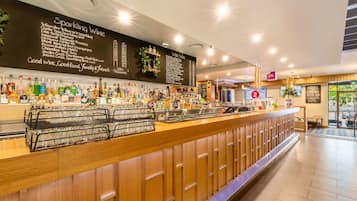 Un espace bar doté d’un tableau noir affichant la carte des vins et d’un comptoir où sont exposées différentes bouteilles.
