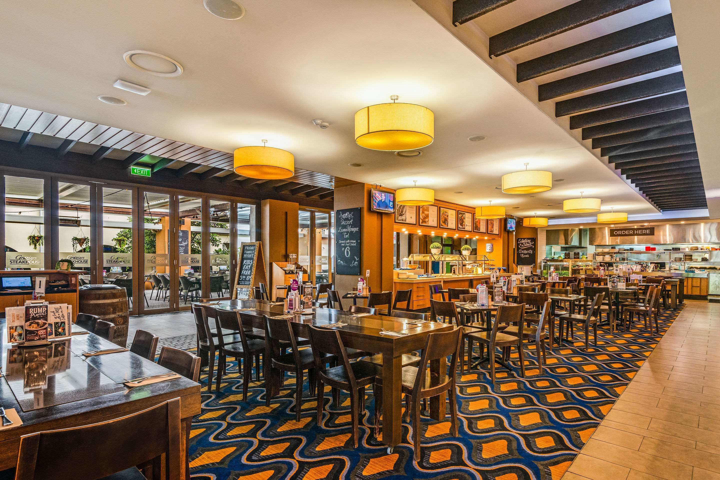 Un restaurante amplio con numerosas mesas y sillas, una zona de bar y una escalera que lleva a un nivel superior.