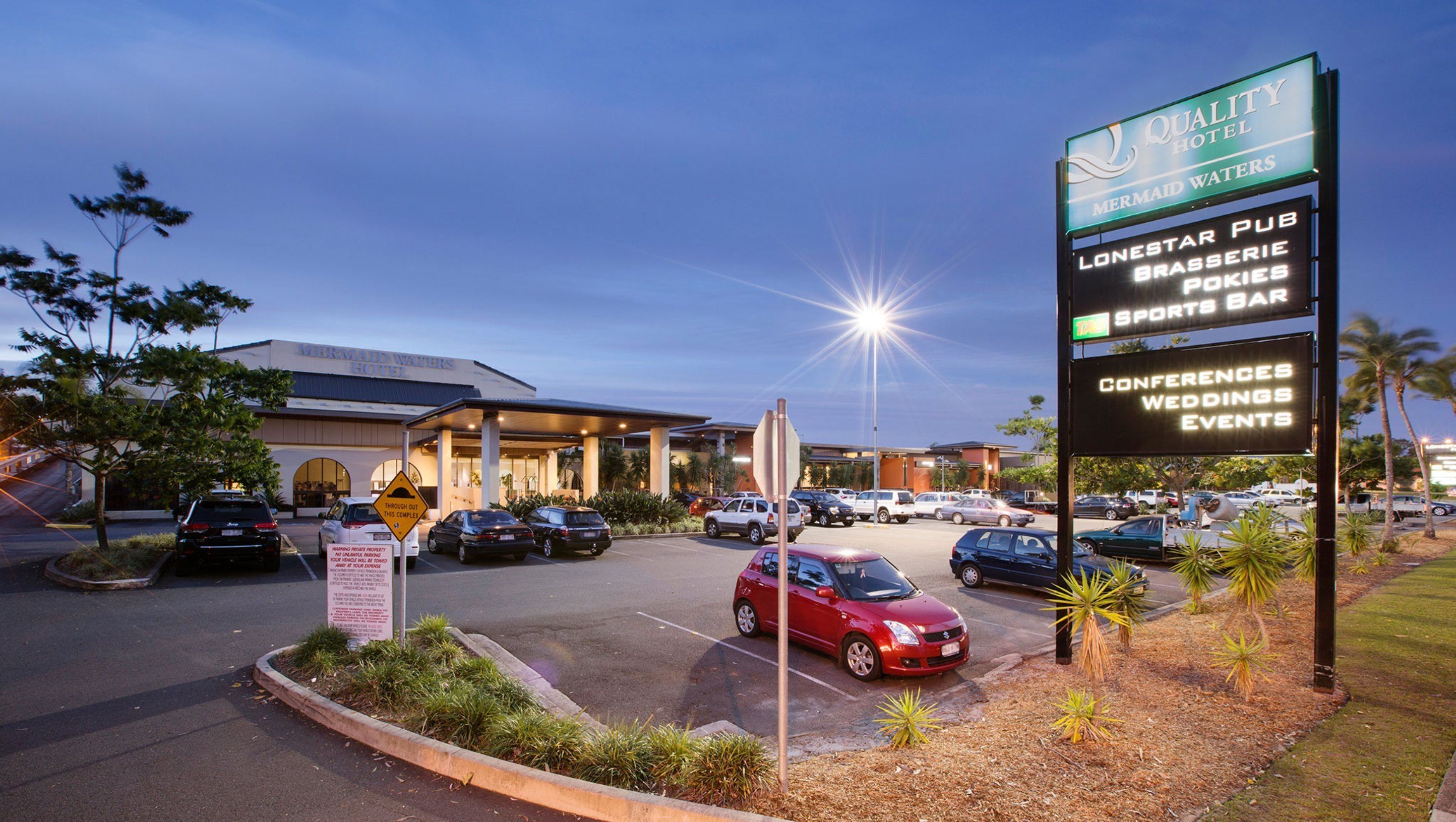 A hotel with a signboard indicating amenities like a pub, sports bar, and conference facilities.