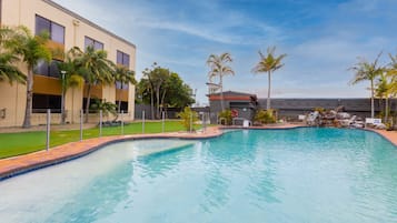 Een buitenzwembad, ligstoelen bij het zwembad