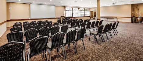 A conference room with rows of chairs, a projector screen, and a large table.
