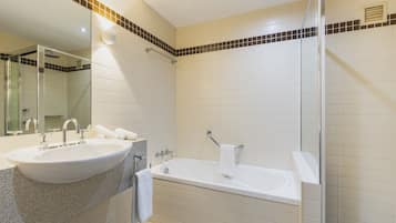 A modern bathroom with a large sink, a bathtub, and a shower area.