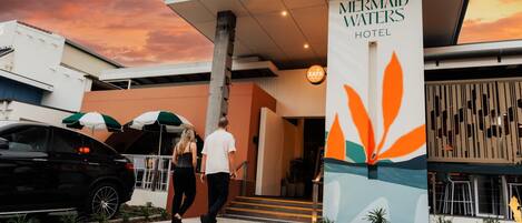 Exterior del hotel Mermaid Waters, con un diseño moderno, una entrada destacada y un letrero que indica el nombre del hotel.