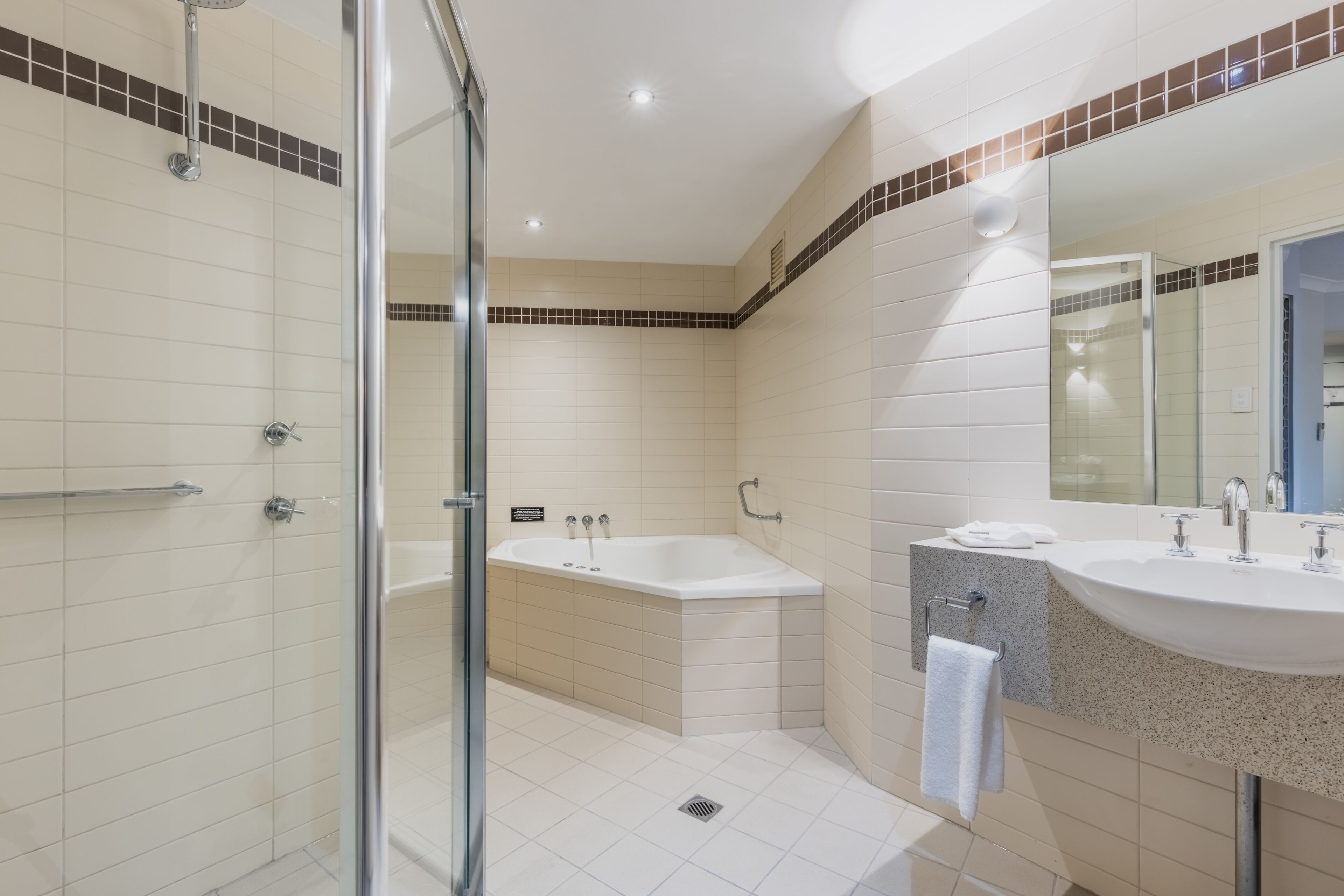A modern bathroom with a glass shower enclosure, a freestanding bathtub, and a vanity with a sink and mirror.