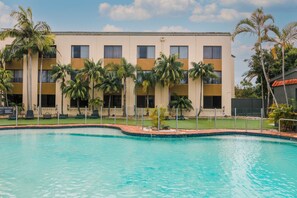 Enjoy a refreshing swim in our pool surrounded by lush palm trees and a beautifully designed facade.