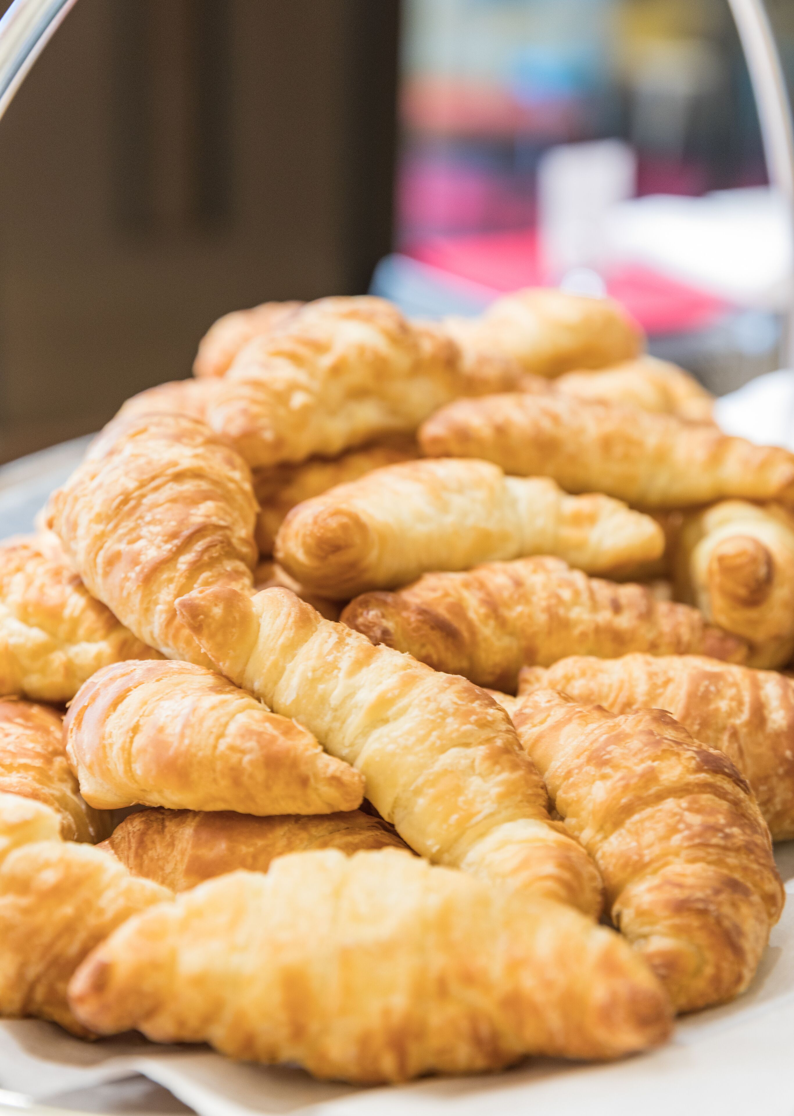 A plate of golden-brown croissants arranged on a white plate.