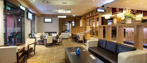 A hotel lobby with a reception desk, seating area, and a staircase leading to other floors.