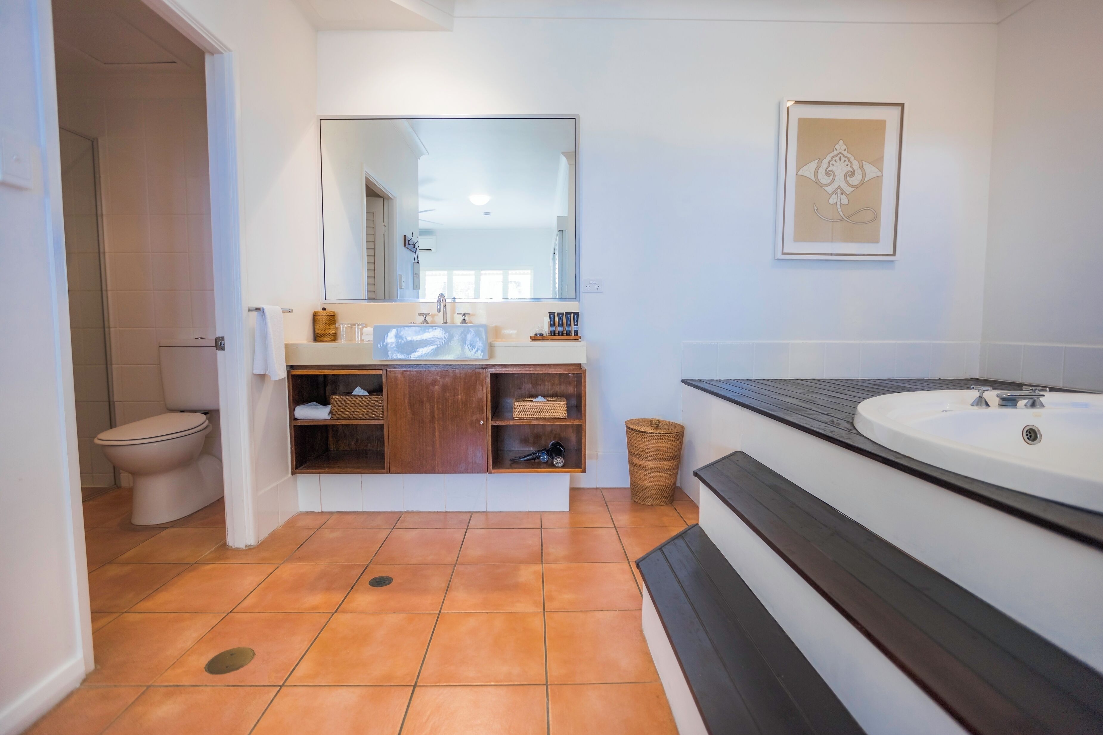 Un baño moderno con un espejo grande, un mueble de tocador de madera, una bañera y un inodoro.