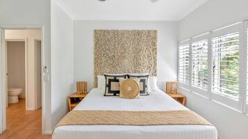 Una camera da letto con un letto grande, una testiera decorativa, due comodini e una finestra con persiane.