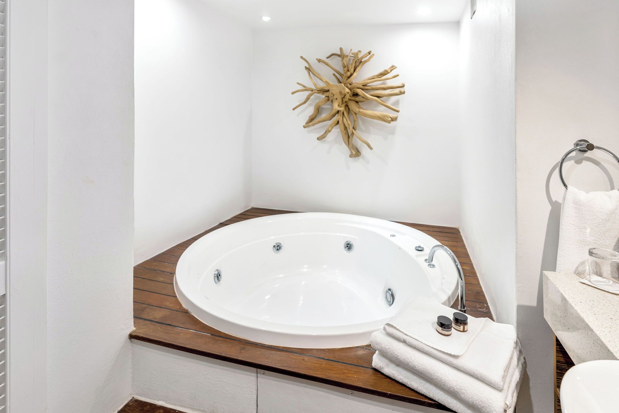 A modern bathroom with a freestanding bathtub, wooden vanity, and a decorative wall piece.