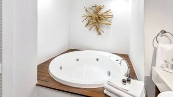 A modern bathroom with a freestanding bathtub, wooden vanity, and a decorative wall piece.