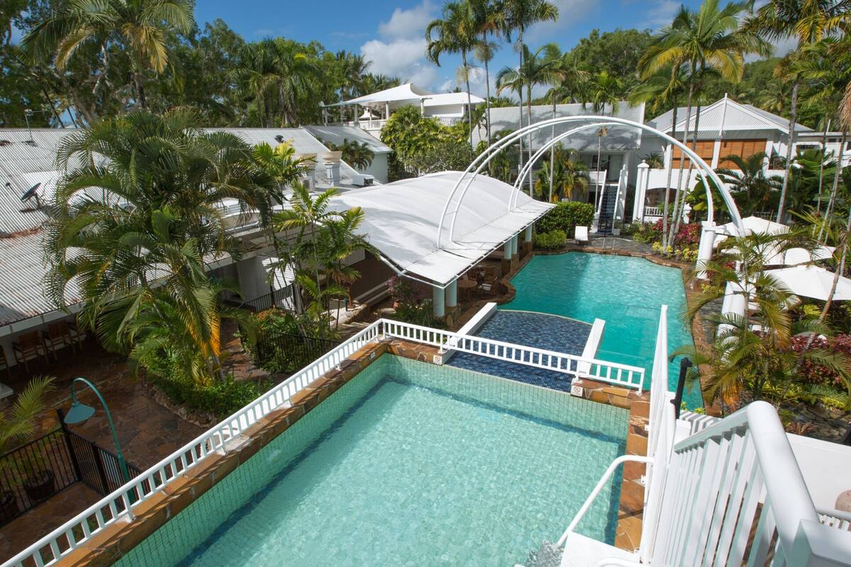 A resort with a swimming pool, covered seating areas, and lush tropical landscaping.