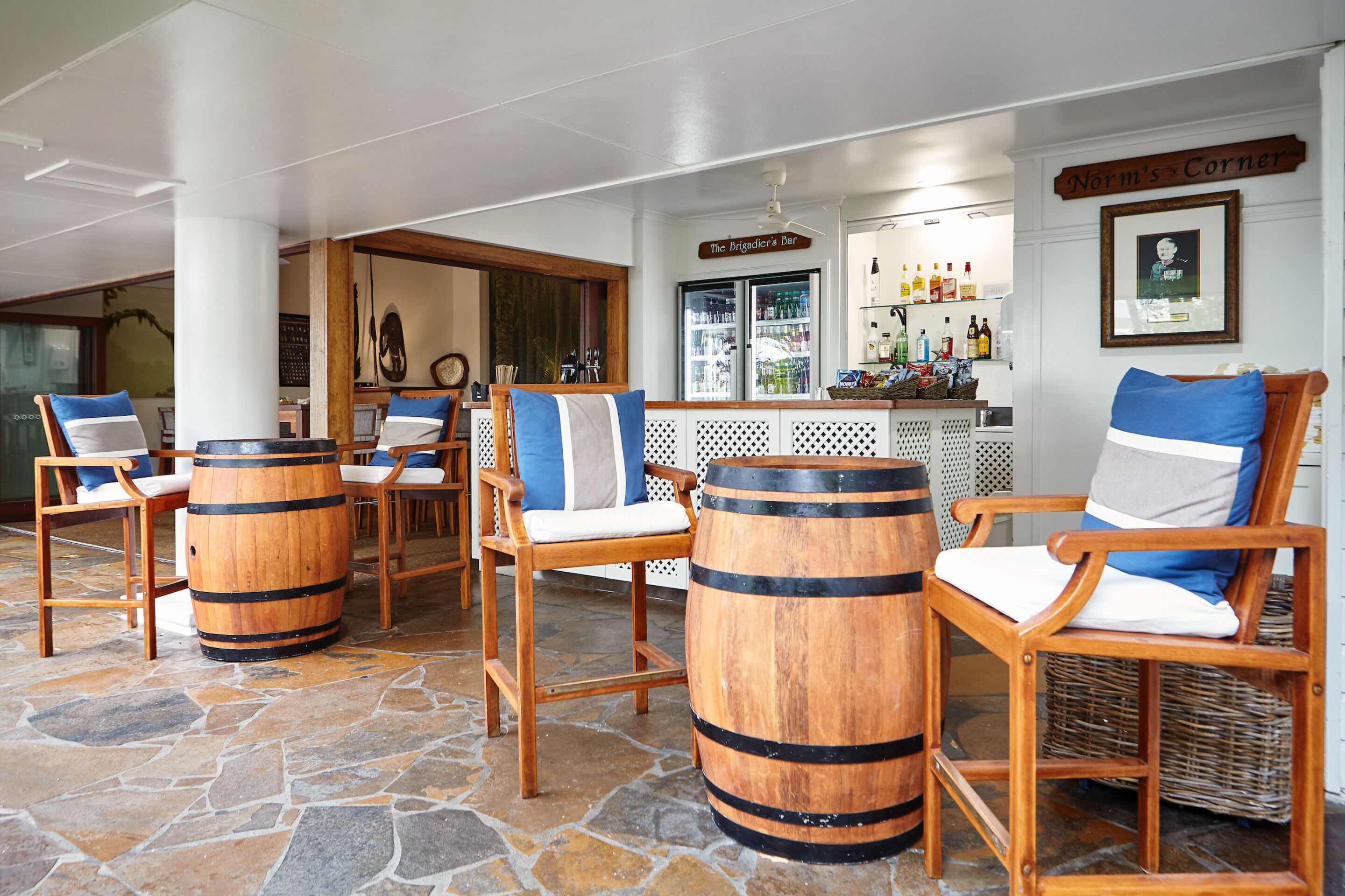 A bar area with wooden chairs and barrels, a sign reading "Norm's Corner", and a bar counter with various bottles.