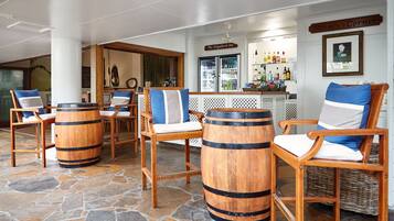 A bar area with wooden chairs and barrels, a sign reading "Norm's Corner", and a bar counter with various bottles.
