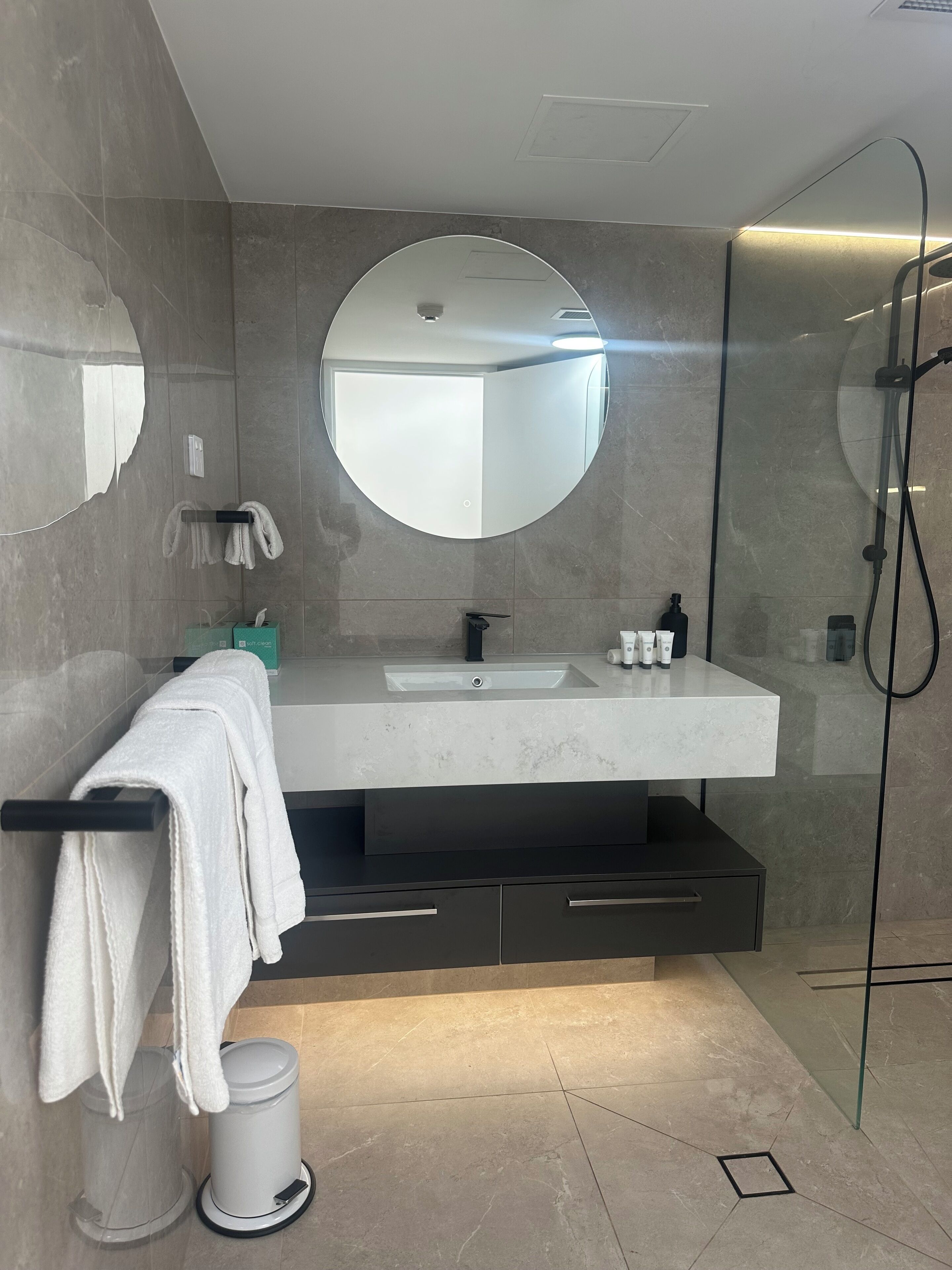 A modern bathroom with a large mirror, a sink, and a shower.