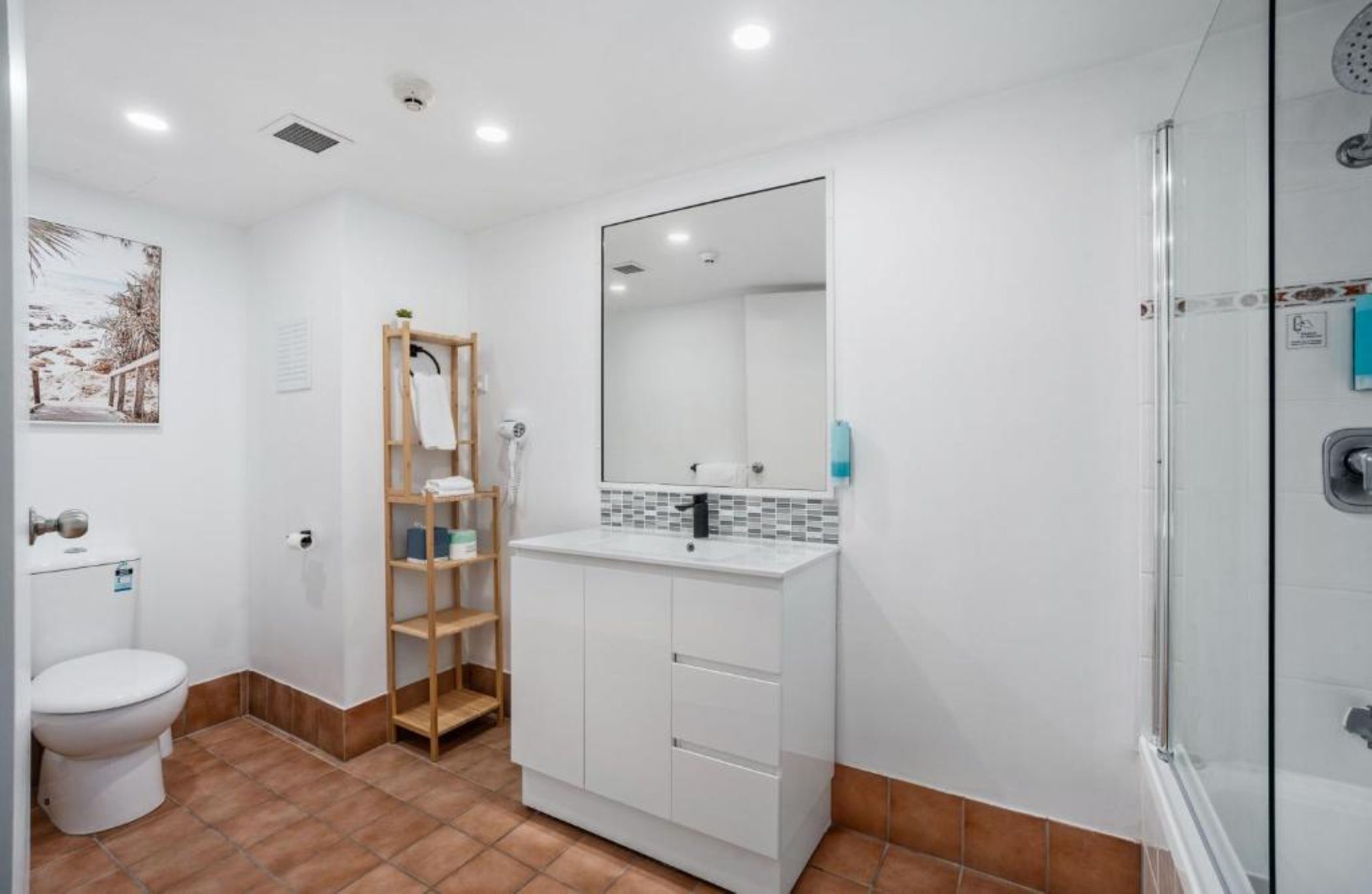 A modern bathroom with a white sink, mirror, and shower.