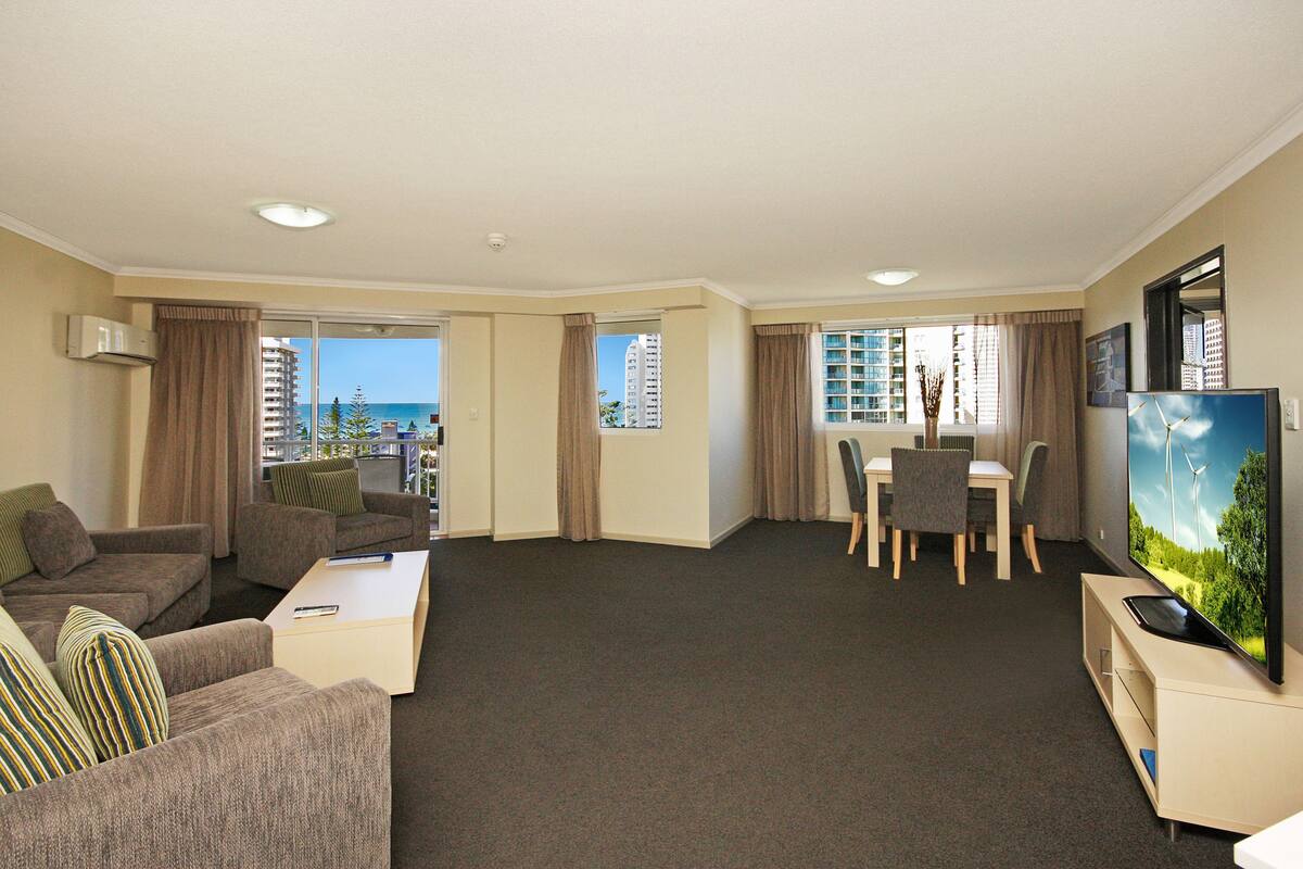 Et hotelværelse med opholdsområde, spisebord og fjernsyn.