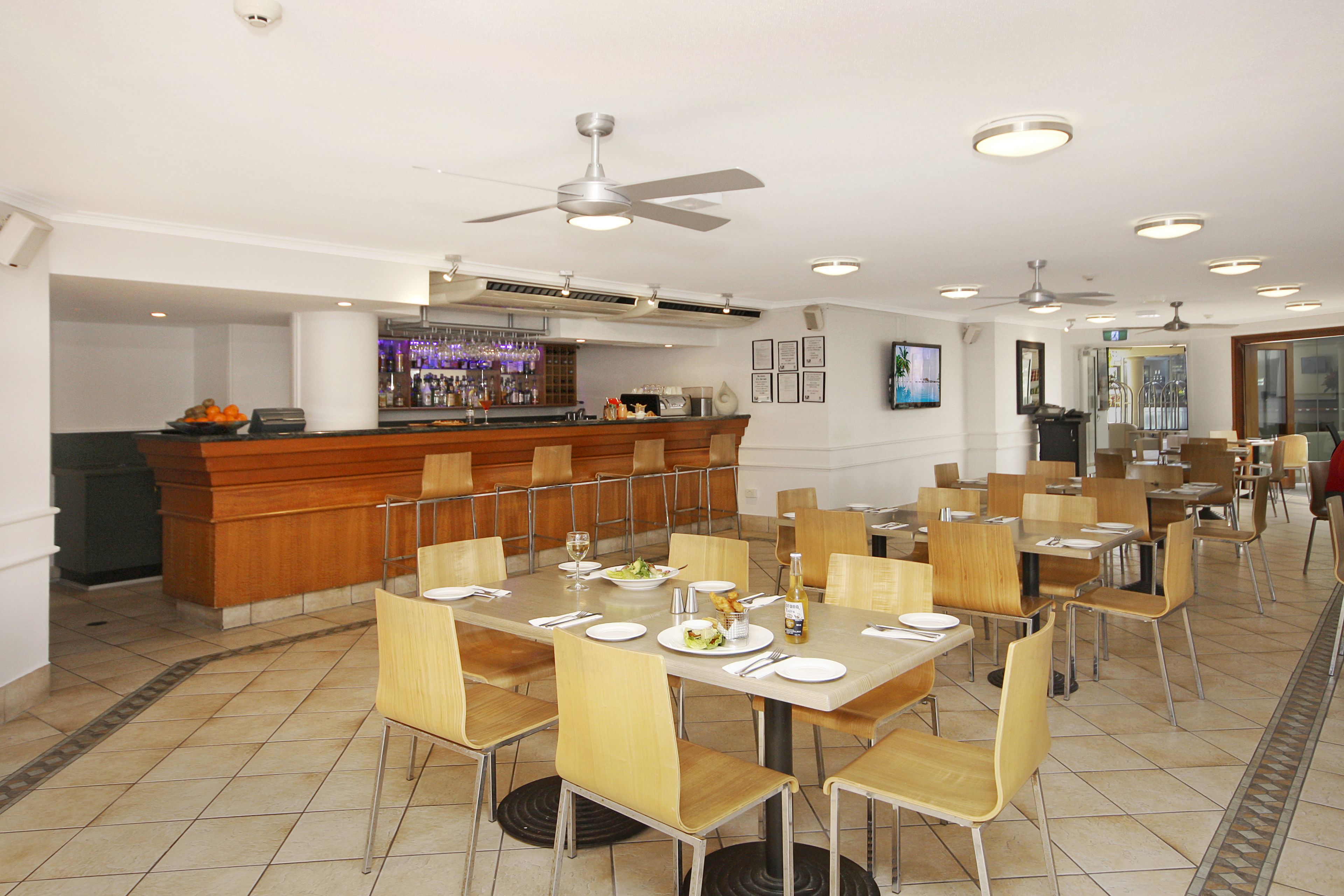 A dining area with multiple tables and chairs, a bar counter, and ceiling fans.