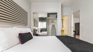 Quarto de hotel moderno com uma cama grande, um closet espaçoso e vista para o banheiro.