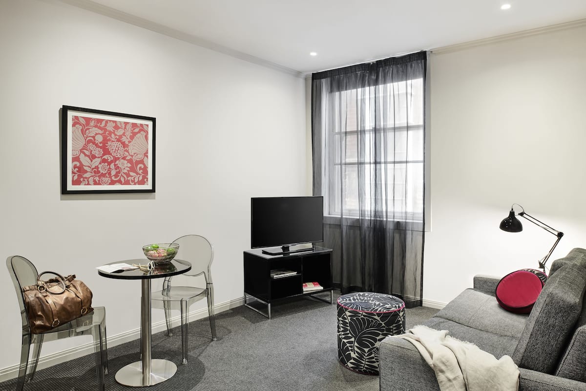Un salon moderne avec un canapé, un meuble pour la télévision, une table en verre et un fauteuil.