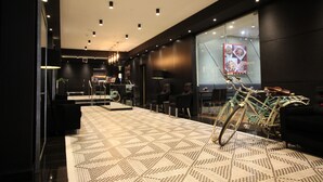 Um hall de hotel moderno com carpete estampado, uma bicicleta e uma área de estar.