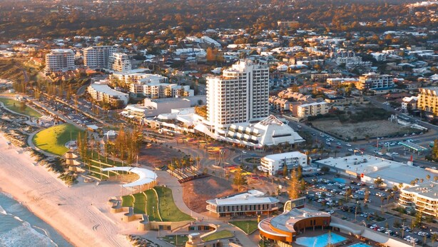An aerial view of a coastal resort with multiple buildings, a beach, and a swimming pool.