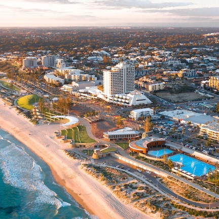 An aerial view of a coastal resort with multiple buildings, a beach, and a swimming pool.
