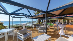 An outdoor seating area with tables and chairs, overlooking the ocean.