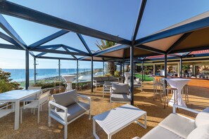 An outdoor seating area with tables and chairs, overlooking the ocean.