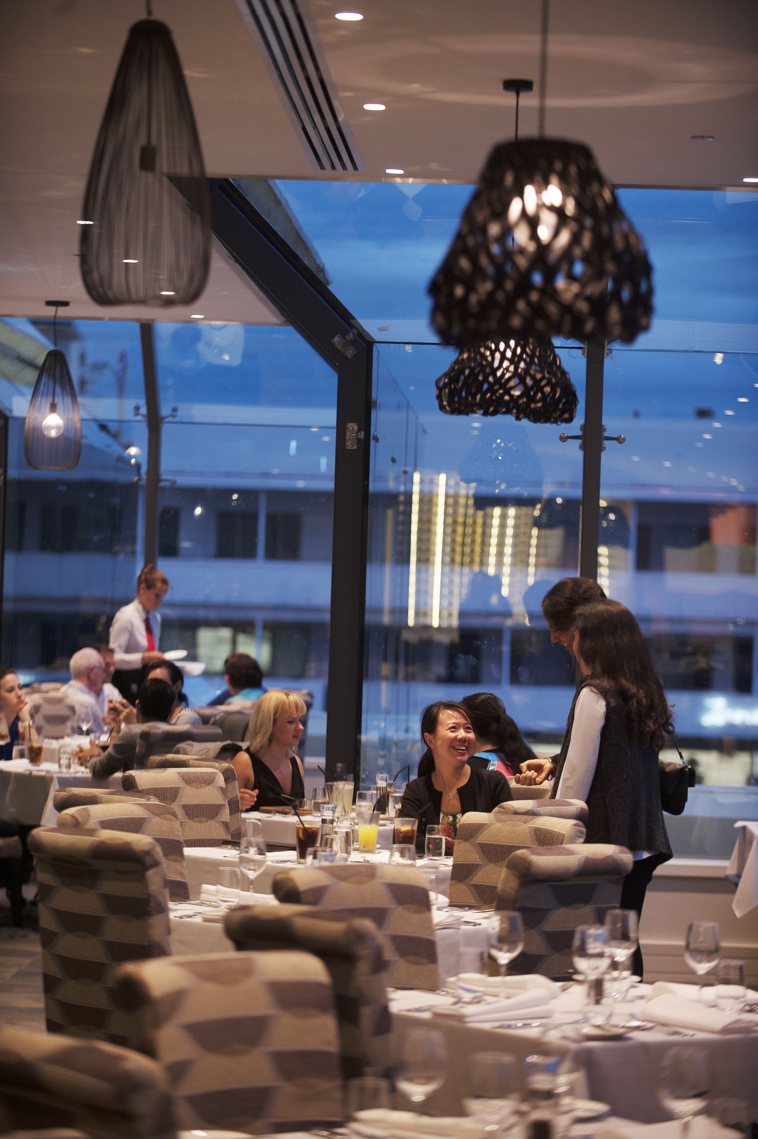 A restaurant with a modern interior, featuring geometric patterned seating and pendant lighting.