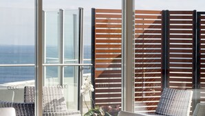 A balcony with a view of the ocean, furnished with chairs and a table. - Rendezvous Hotel Perth Scarborough (Scarborough)