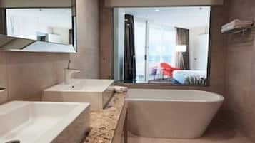 A modern bathroom with a large bathtub, a separate shower area, and a vanity with a mirror.