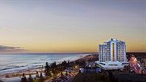 A coastal hotel with a view of the ocean and a sunset.